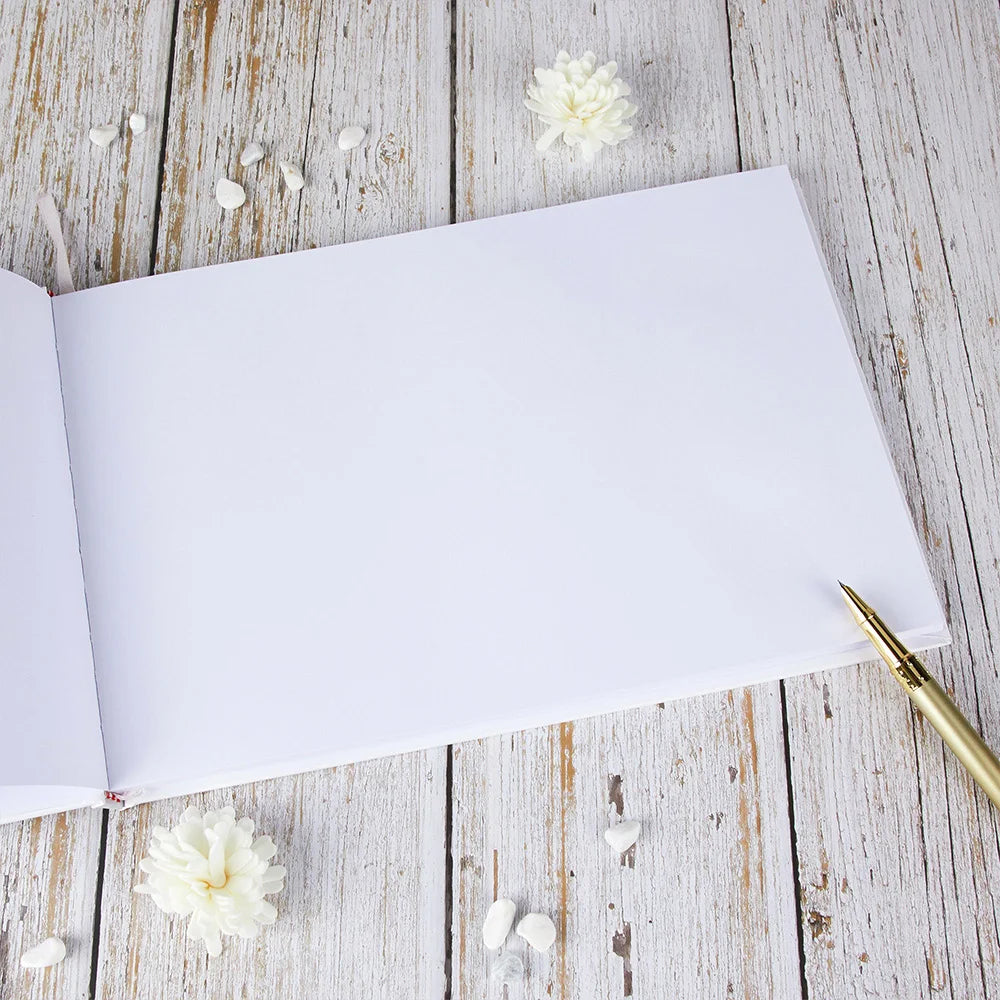 Open wedding guest book with blank white pages and gold pen, white cover spine