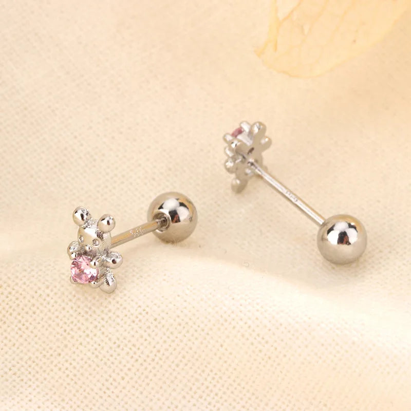 Silver-tone huggie hoop earrings with small pink crystal flower charm