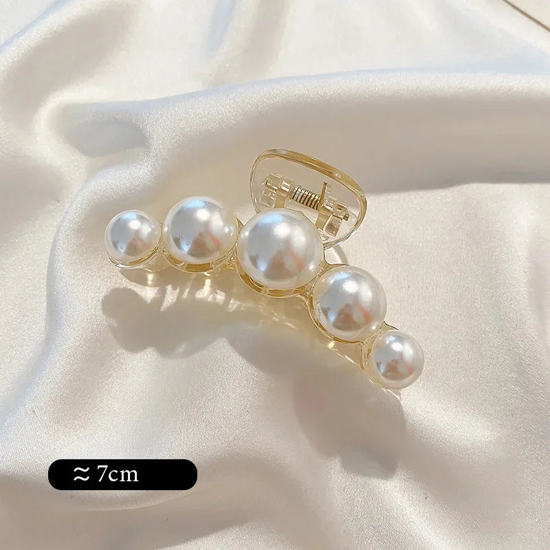Pearl claw hair clip with gold-tone frame and white faux pearls; ~7cm.