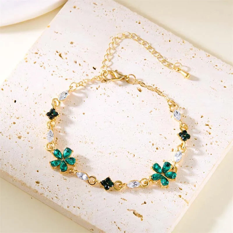 Gold-tone crystal bracelet with green flower charms and clear teardrop stones