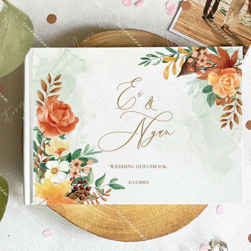 Wedding guest book cover with orange floral corner accents and script names; 2/11/2023