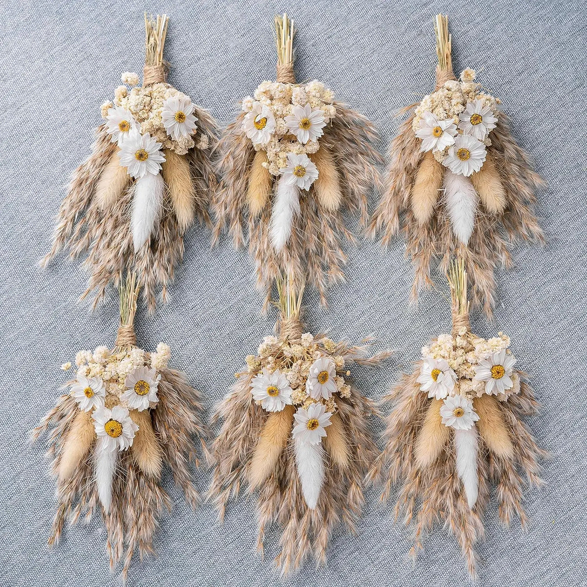 Set of tan dried flower boutonnieres with white daisies, fluffy pampas plumes, and straw stems