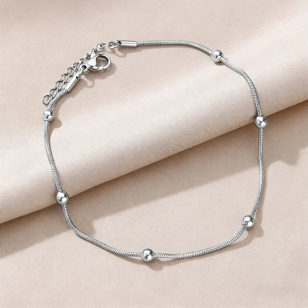 Silver-tone bracelet with pearl-like beads and round charm stations, toggle clasp
