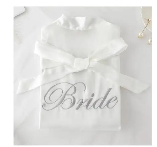 White satin robe with embroidered “Bride” script on the chest and ruffled neckline