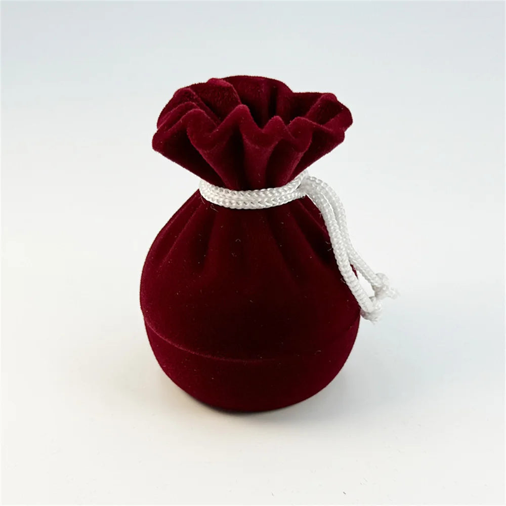 Wine red velvet ring pouch with pleated top and drawstring cord.