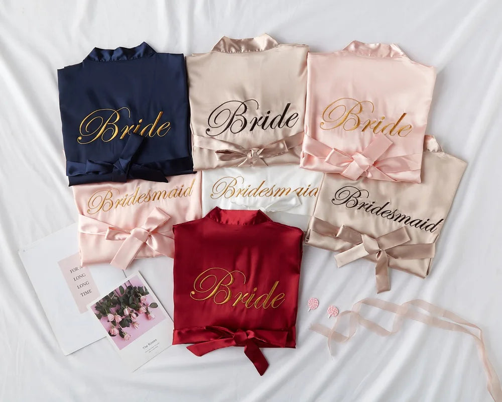 Satin bridal robe set with embroidered “Bride” and “Bridesmaid” text in blush tones