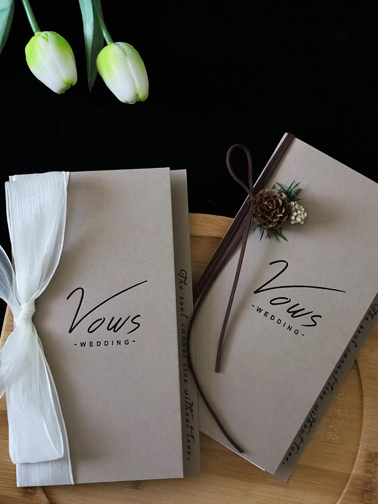 Ivory vows booklet set with gold-foil text, tied with white ribbon and small floral accents