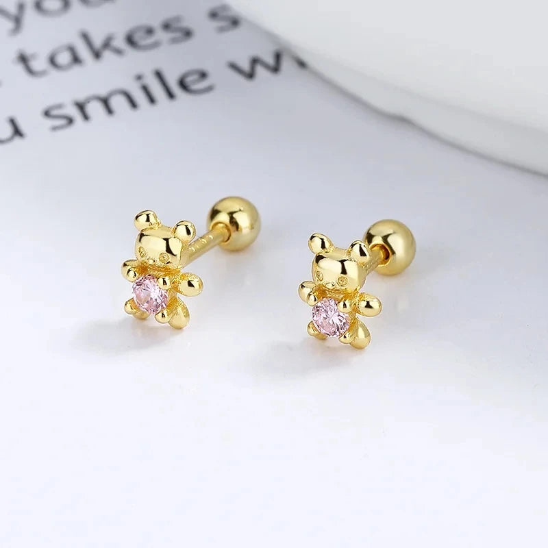 Gold-tone stud earrings with four-petal flower and pink crystal center