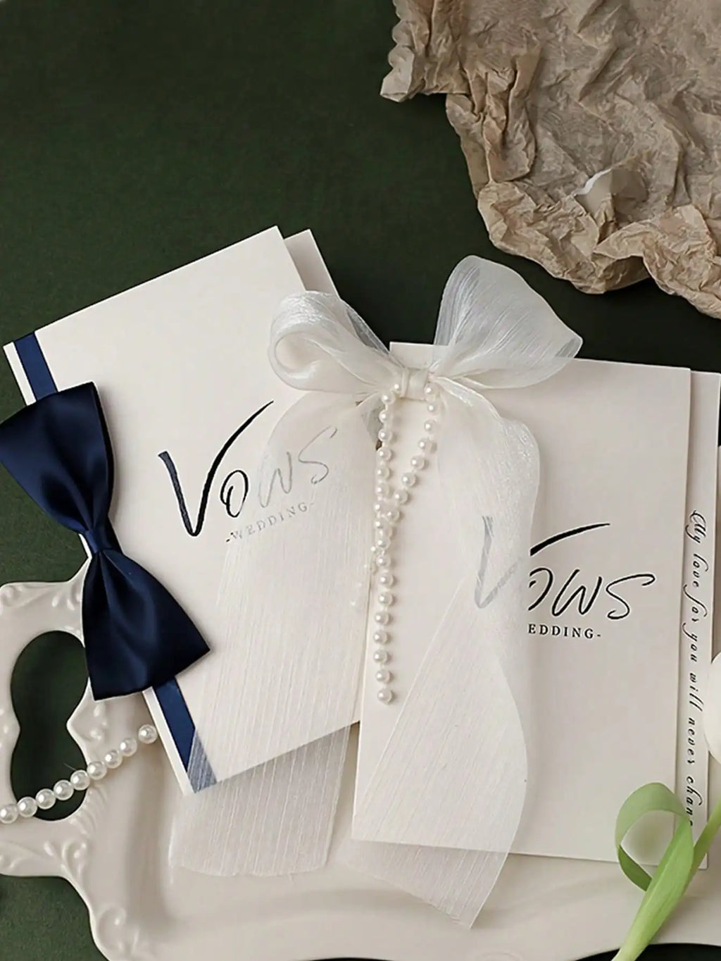 Wedding vow booklet with 'Vows' cover, white ribbon bow, navy ribbon accent, and pearl beads