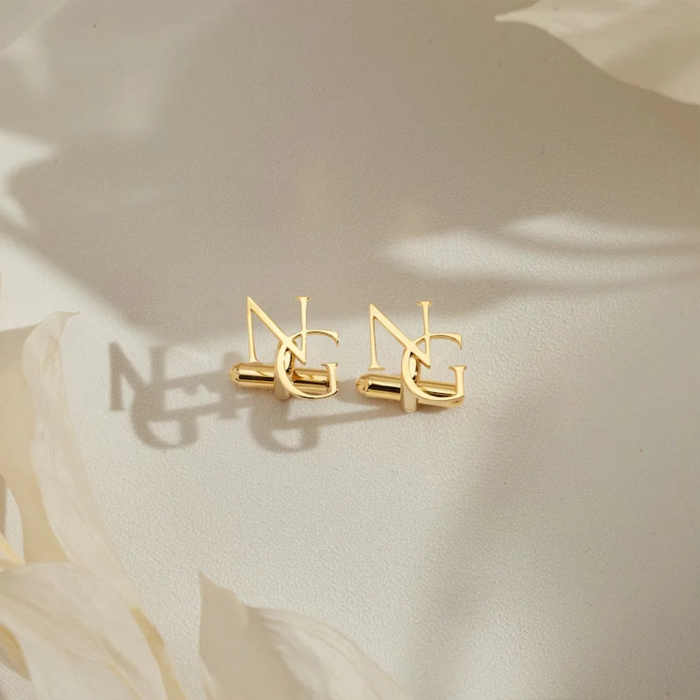 Gold monogram cufflinks with interlocking initials, close-up of two pieces