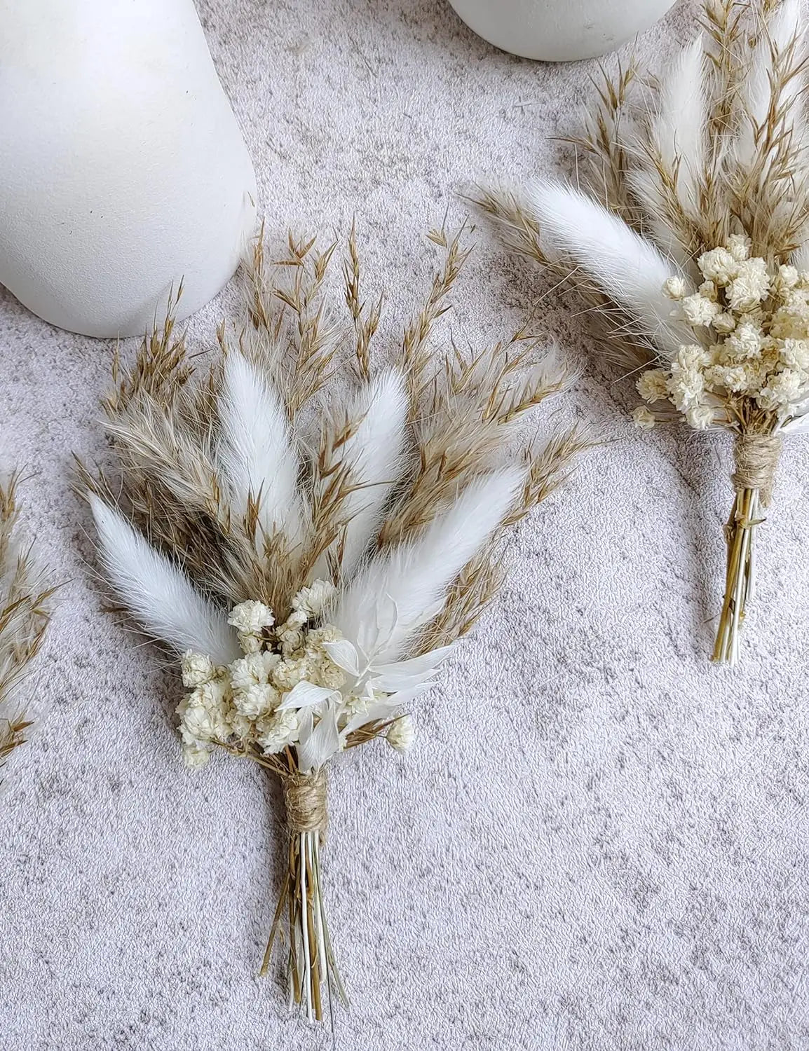 Dried flower boutonnière with tan pampas plumes, white blossoms, and tied gold-stem bundle