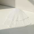 Bride-to-be pearl veil with “bride to be” script across white tulle, ribboned edge