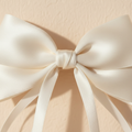 Off-white satin bow hair clip close-up with long ribbon tails