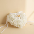 White heart-shaped rose ring bearer pillow with pearl accents and satin ribbons