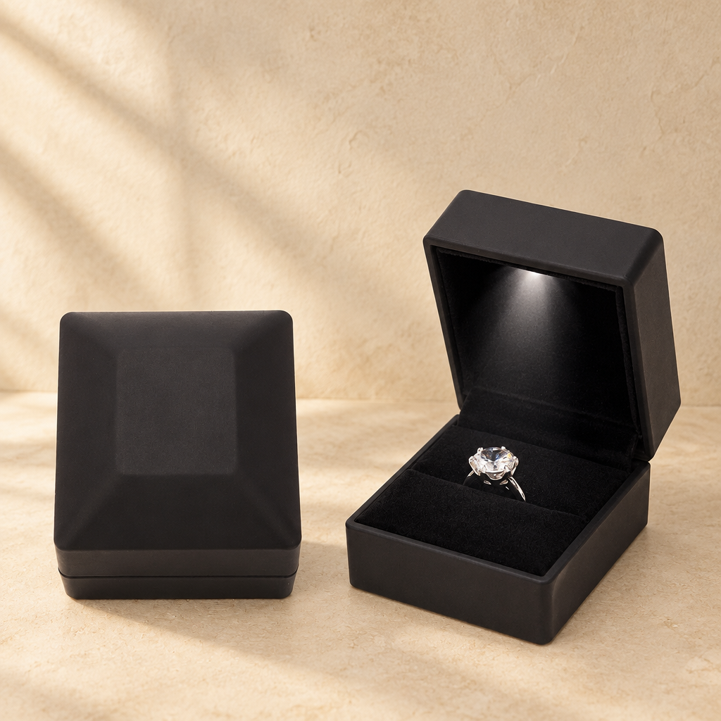 Black LED proposal ring box with open lid and ring on black velvet insert.
