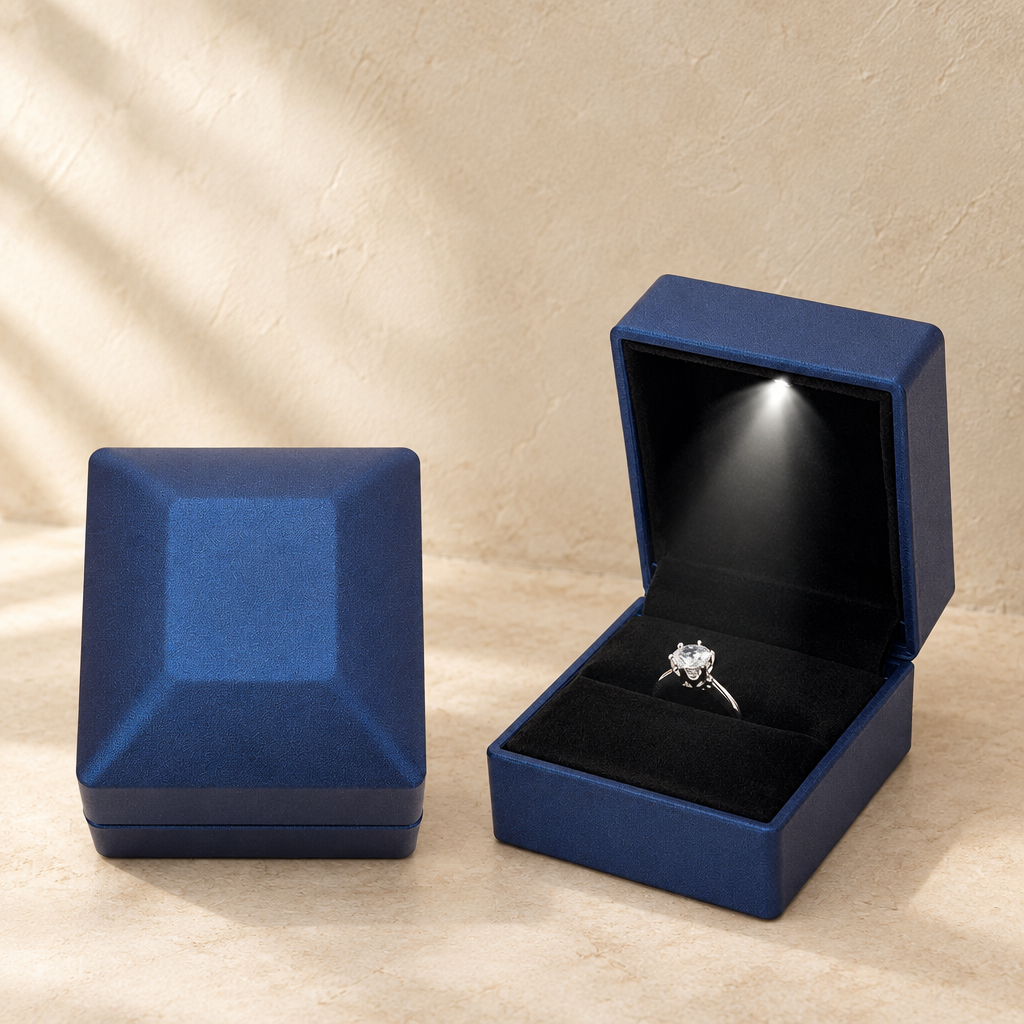 Blue LED proposal ring box with open lid and ring on black velvet insert.