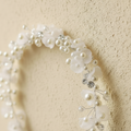 White beaded trumpet wreath headband close-up with pearl flowers and crystal accents